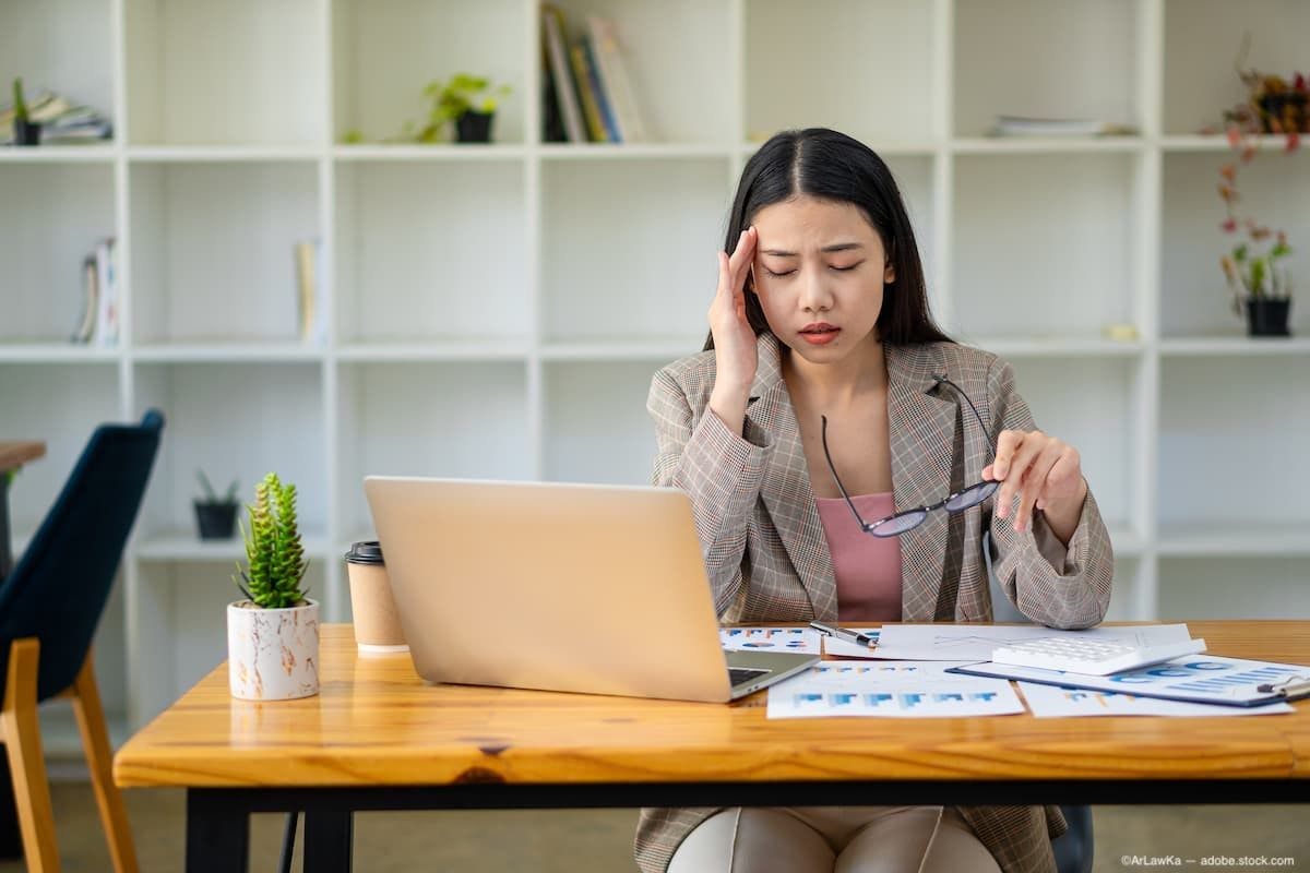 Business woman holding glasses and her temple at a desk with a computer Image Credit: AdobeStock/ArLawKa