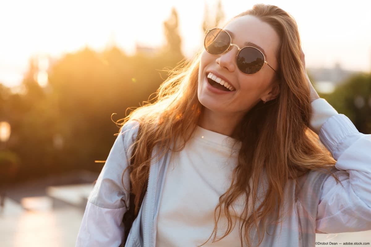 Woman smiling outside with sunglasses on Image Credit: AdobeStock/Drobot Dean