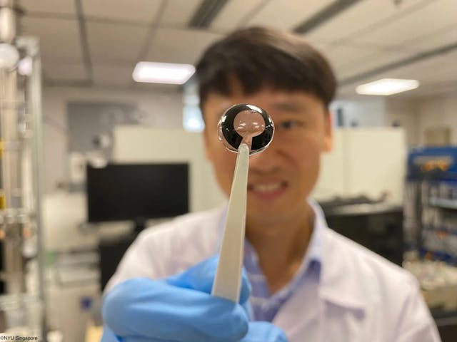 Member of research team holds up flexible battery for smart contact lenses Image credit: NYU Singapore