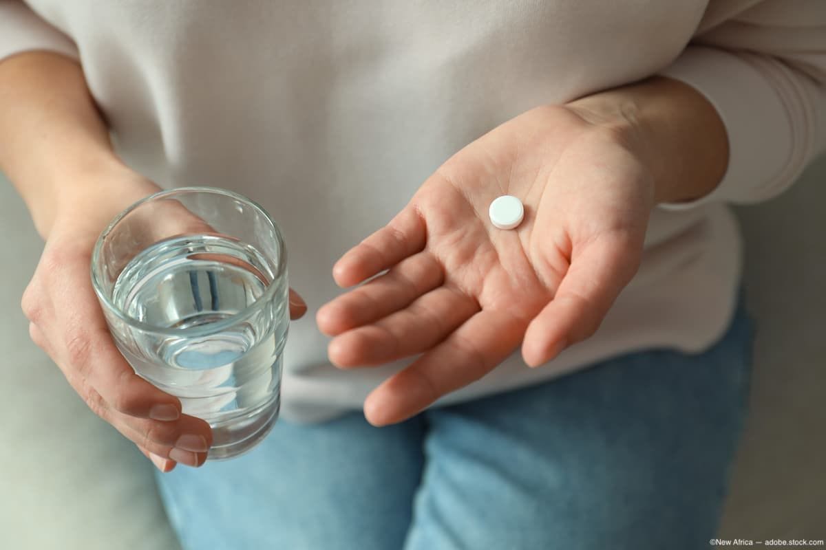 Woman holding pill and glass of water while sitting down Image Credit: AdobeStock/NewAfrica