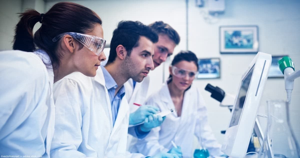 Team of researchers in a lab looking at desktop computer Image credit: AdobeStock/vectorfusionart