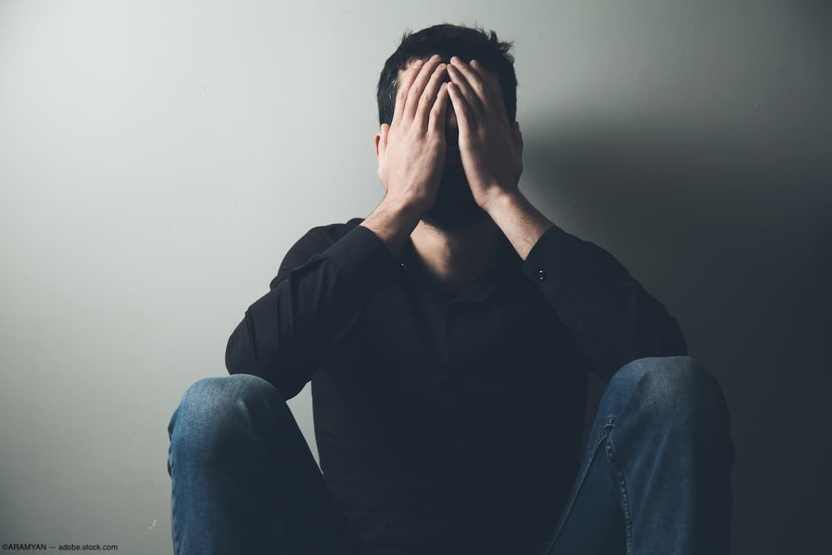 Depressed man sitting with head in hands Image credit: AdobeStock/ARAMYAN