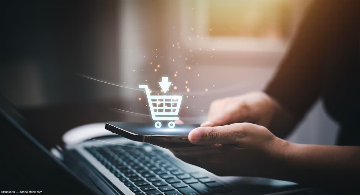 Phone held in woman's hand with shopping cart graphic Image credit: AdobeStock/Bussarin