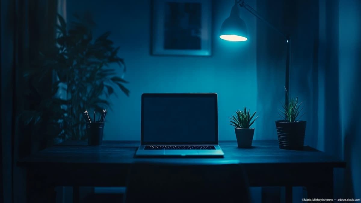 Blue light illuminates empty desk with laptop Image credit: AdobeStock/Maria Mikhaylichenko/AI