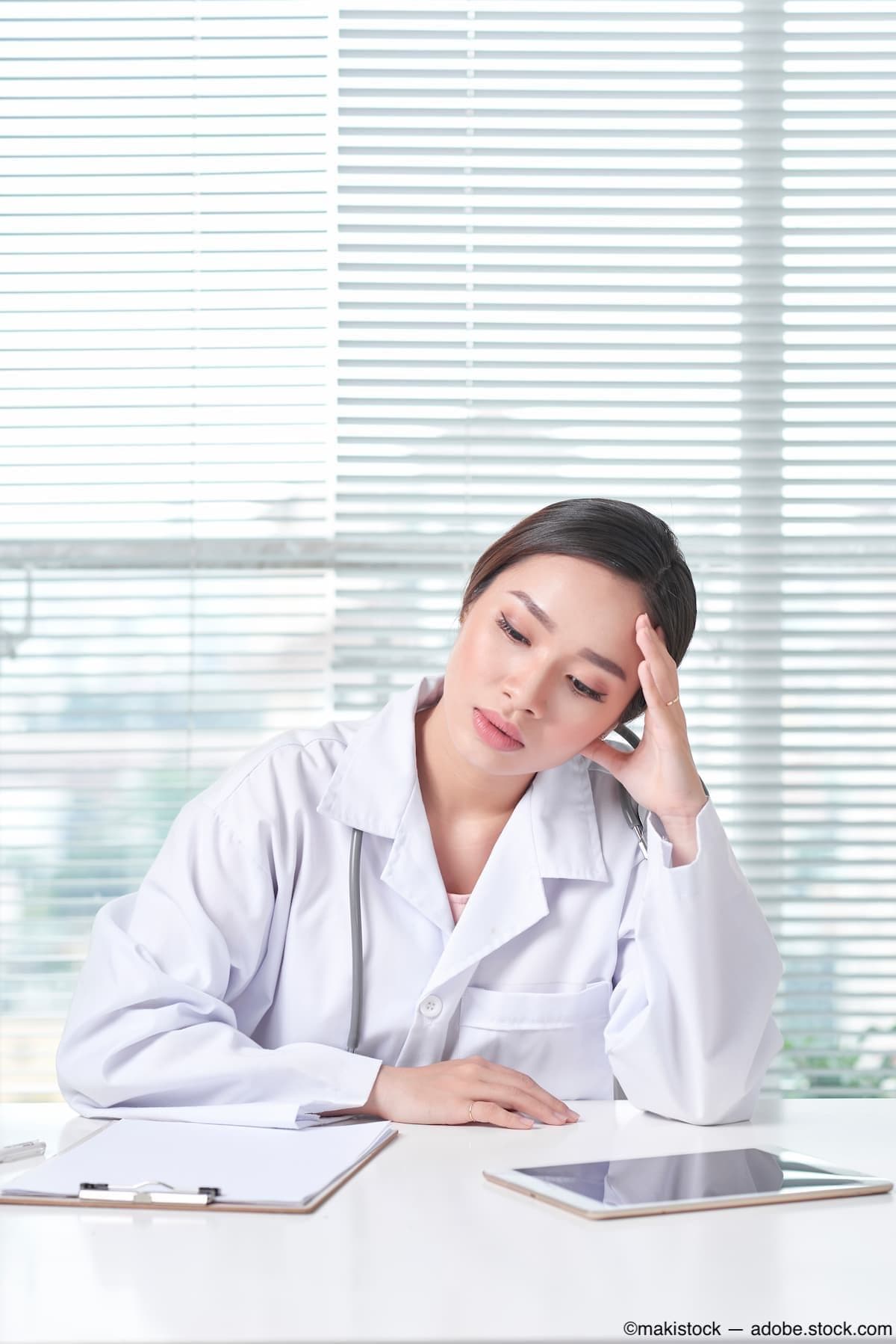 Frustrated doctor sitting at desk Image credit: ©makistock - adobe.stock.com