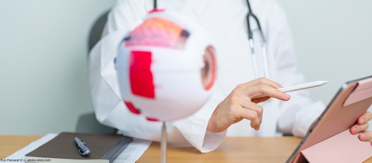 Doctor sitting at desk with medical eye figure Image credit: AdobeStock/JoPanuwatD