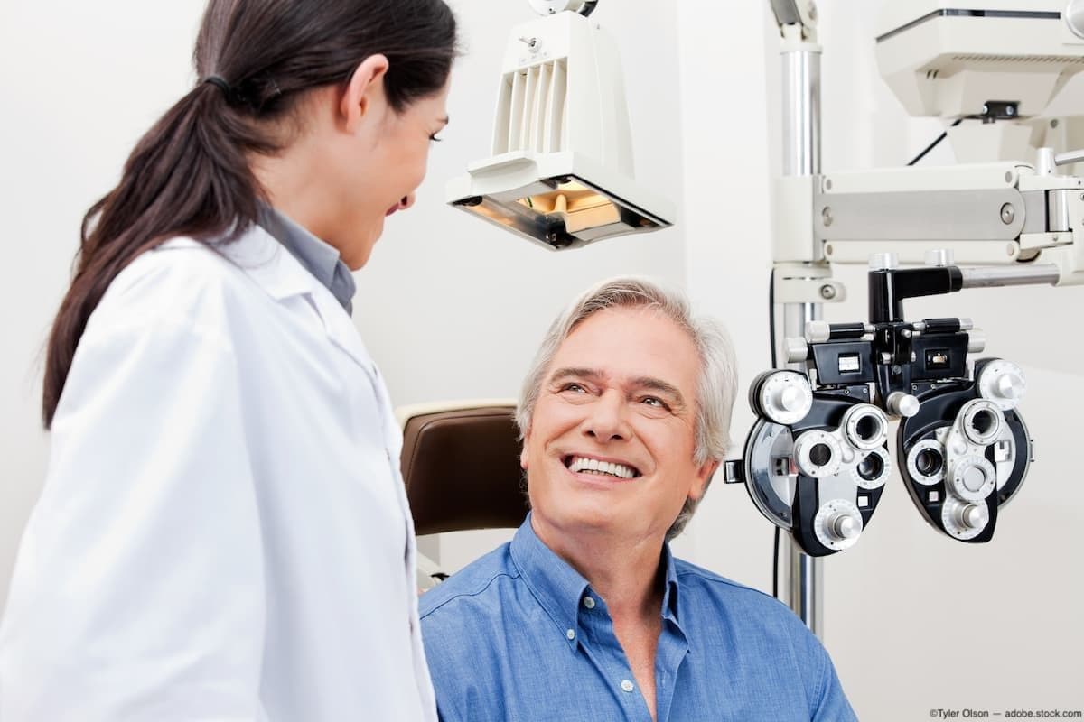 Patient smiling at optometrist and sitting for eye exam Image credit: AdobeStock/TylerOlson