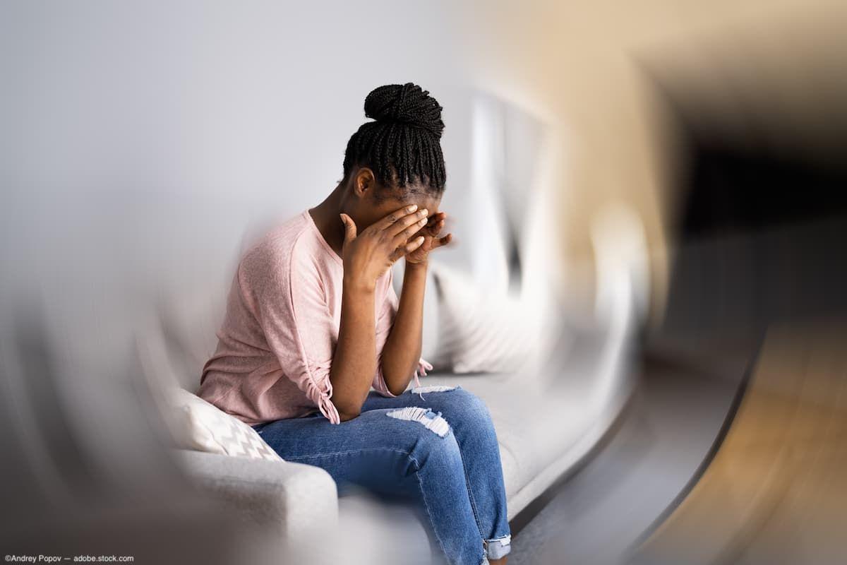 Woman experiencing migraine on couch with blurry background Image credit: AdobeStock/AndreyPopov