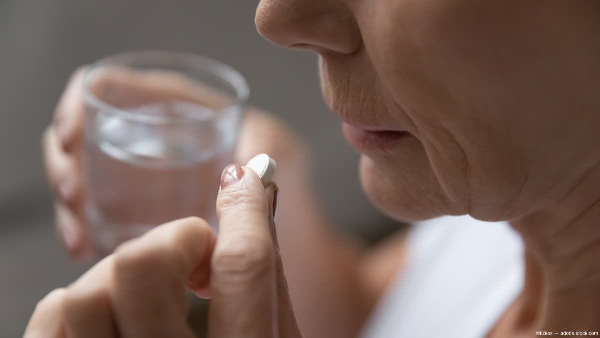 Older woman taking aspirin with water