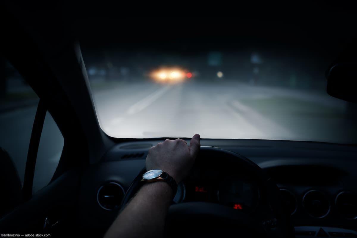 Drivers perspective behind the wheel of a car at night Image credit: AdobeStock/ambrozinio